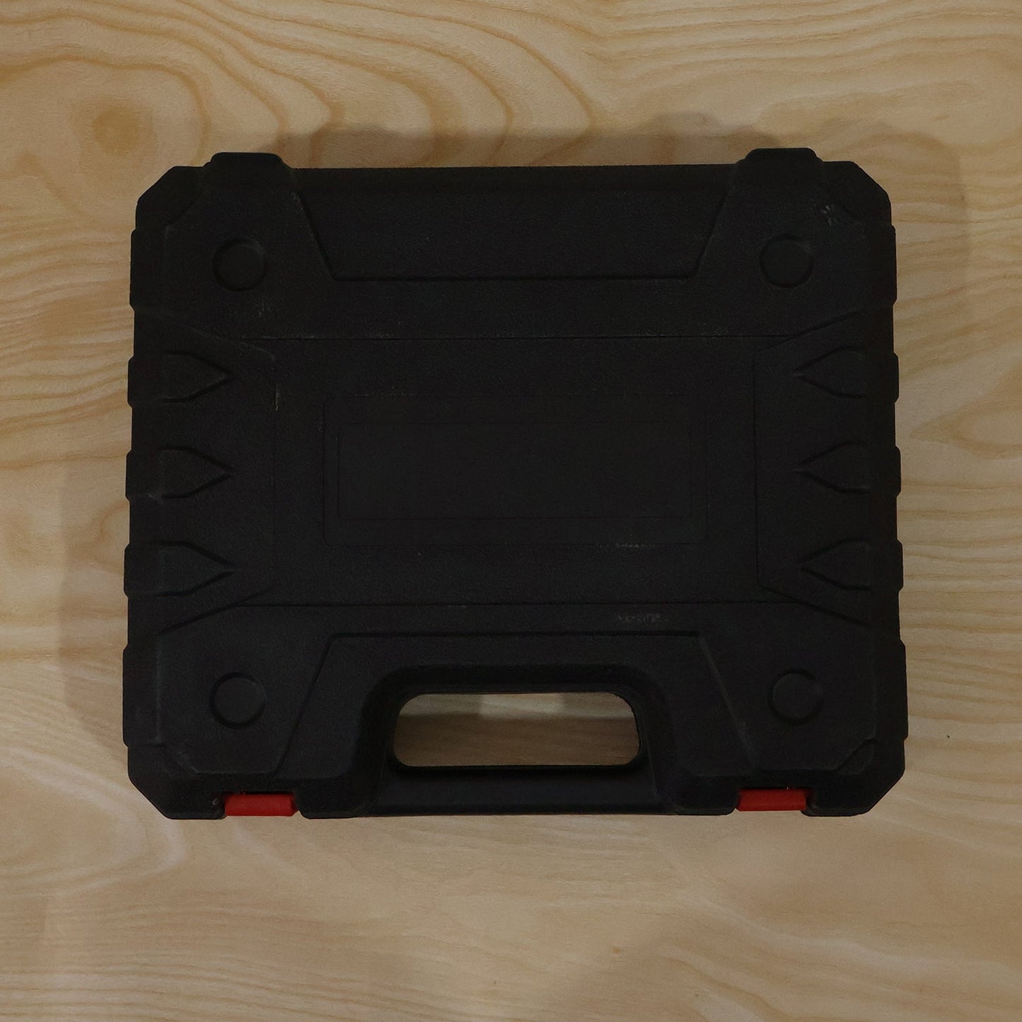 A closed black plastic carrying case with orange latches rests on a light wooden surface.