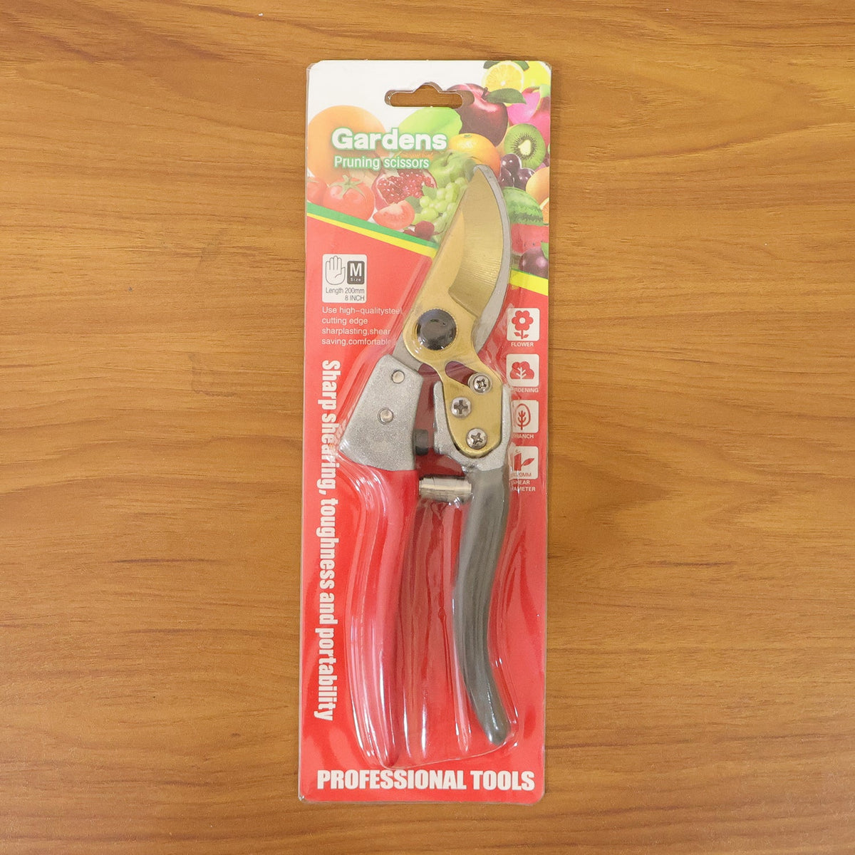 Red and grey garden shears with gold blades visible through clear plastic packaging, featuring fruit graphics and text