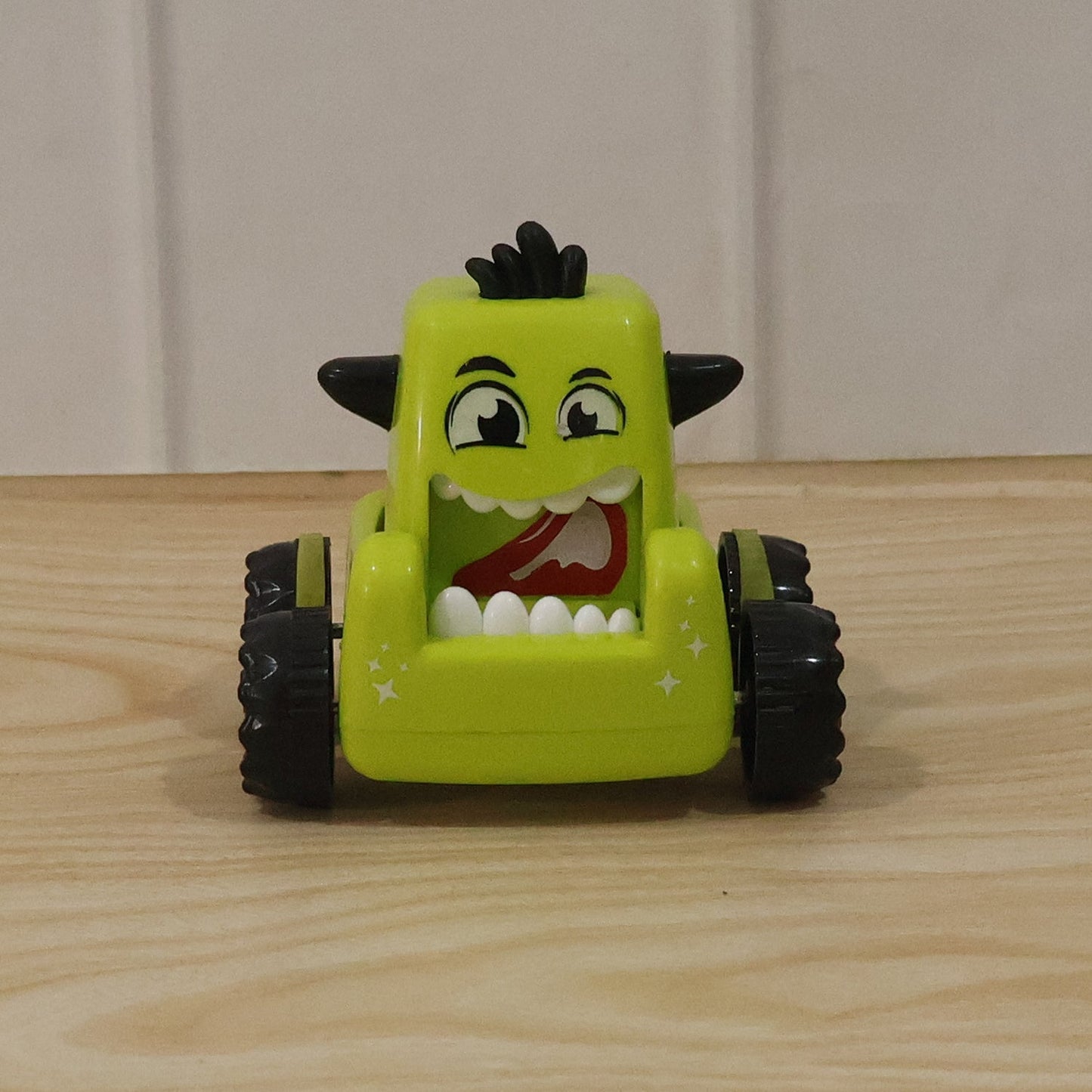 Child outdoors playing with a green cartoon monster car toy