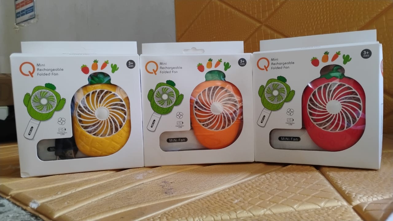Three packaged mini fans, shaped like a green vegetable, a yellow pineapple, and a red strawberry, are displayed