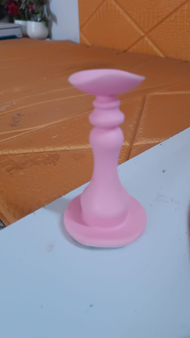 Pink silicone door stopper standing on a light blue surface with an orange textured background.