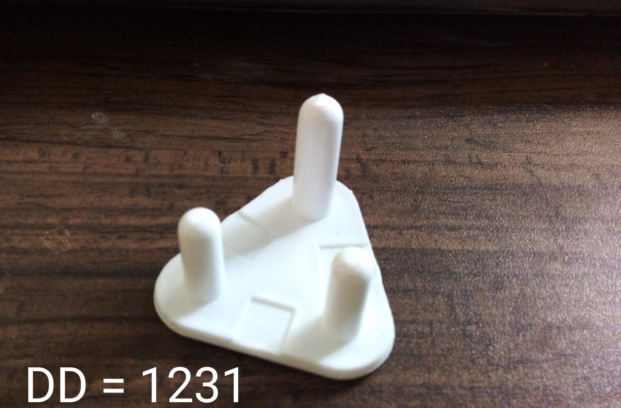 A white 3-pin socket cover rests on a dark wooden surface, with the text 'DD = 1231' in the bottom left corner.