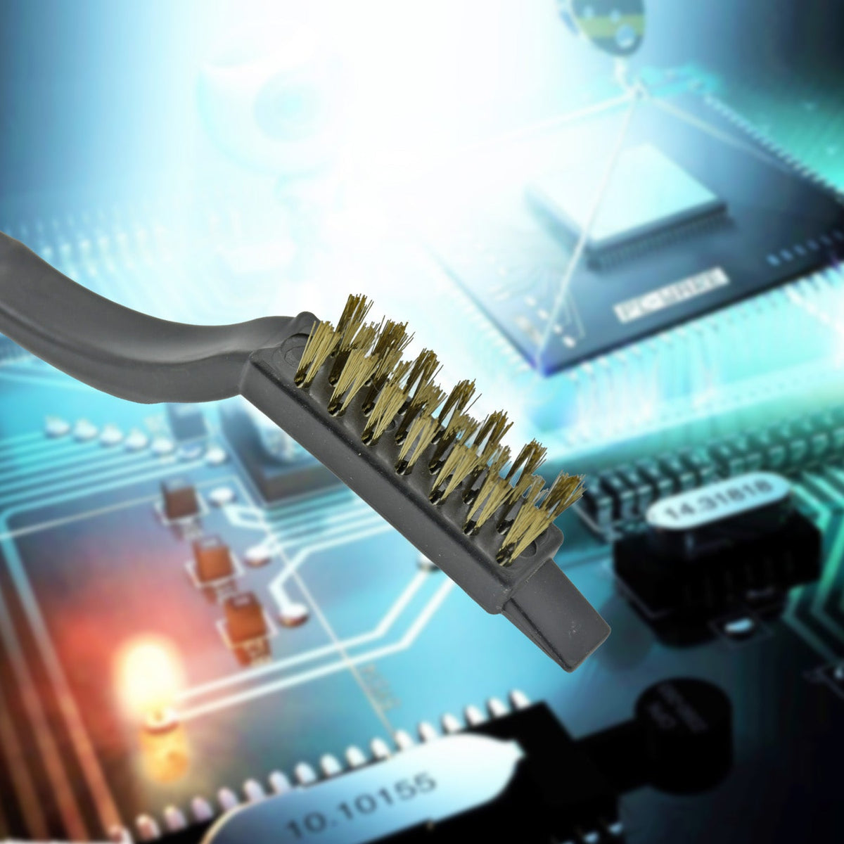 A close-up of a black-handled mini wire brush with brass bristles, set against a blurred background of a glowing circuit