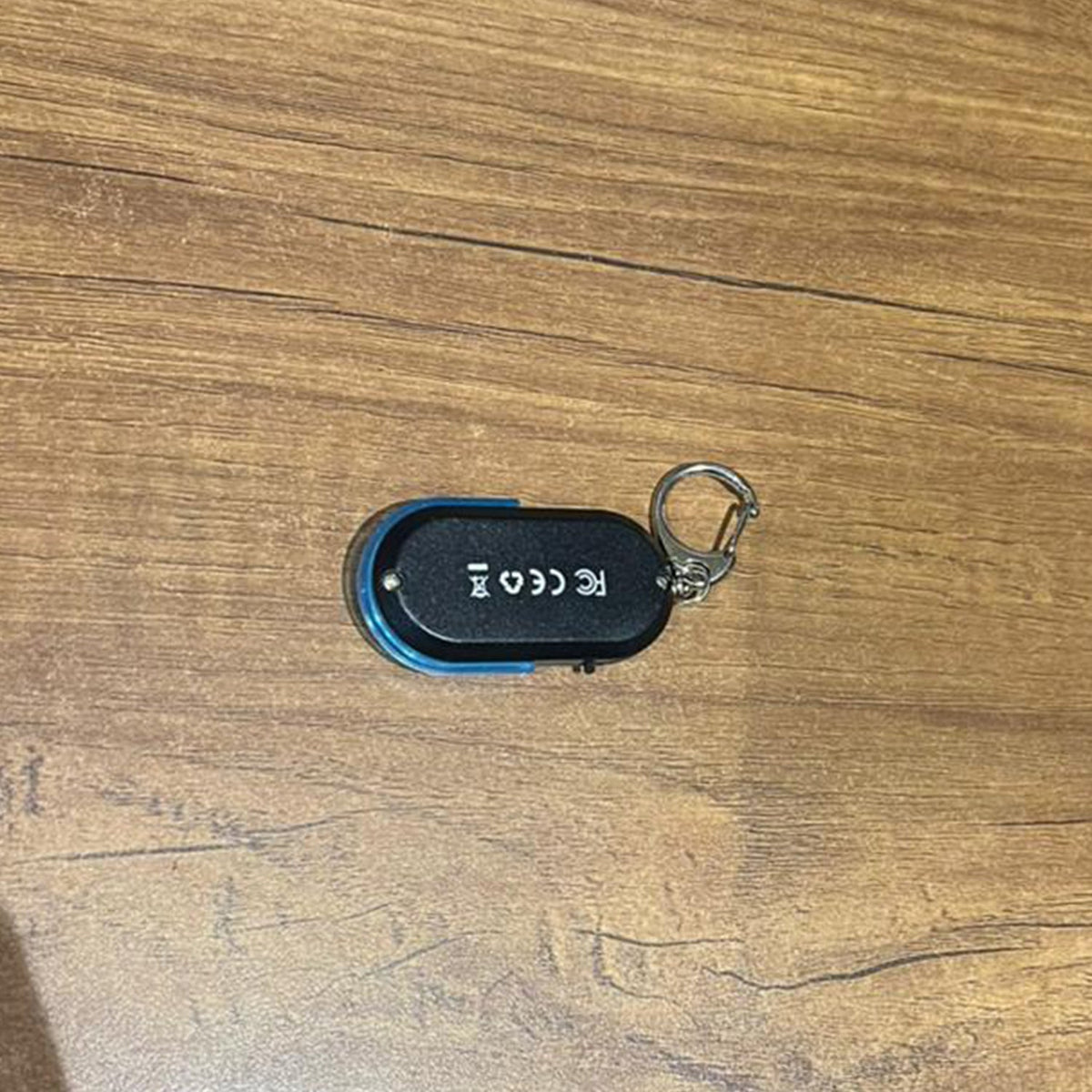 A black and blue personal safety alarm keychain with a silver carabiner clip is attached to a black leather handbag.