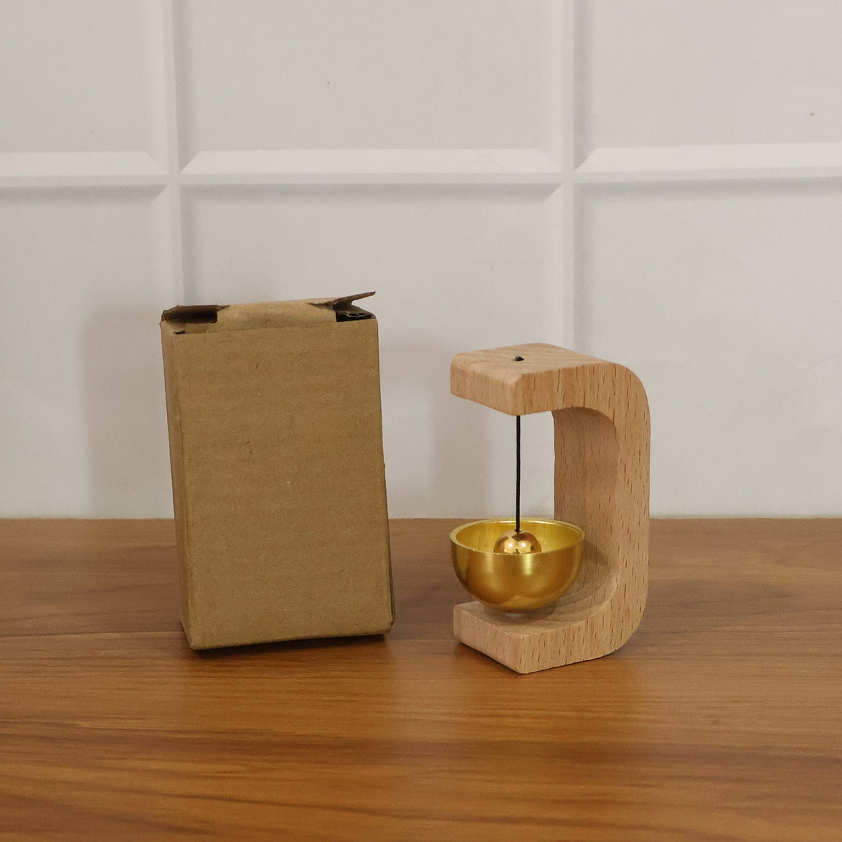 Magnetic wooden door chime bell positioned on its stand bathed in natural light.