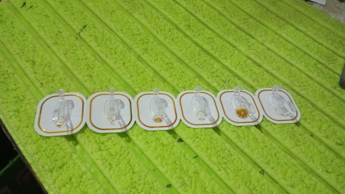 Six transparent adhesive hooks with gold borders laid out on a textured green surface.