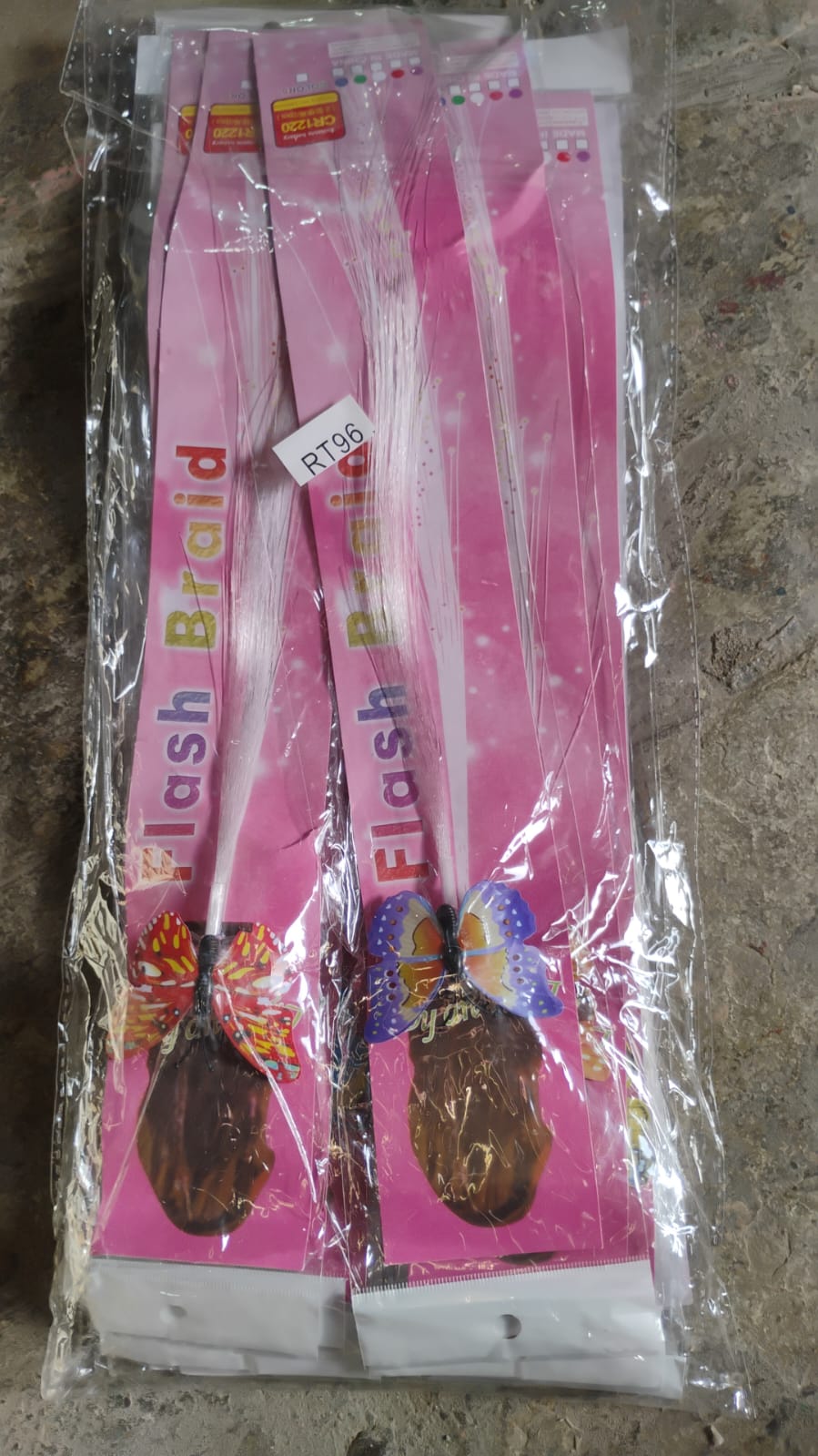 Multiple packaged light-up butterfly hair braids with pink backing cards are visible through clear plastic wrapping.