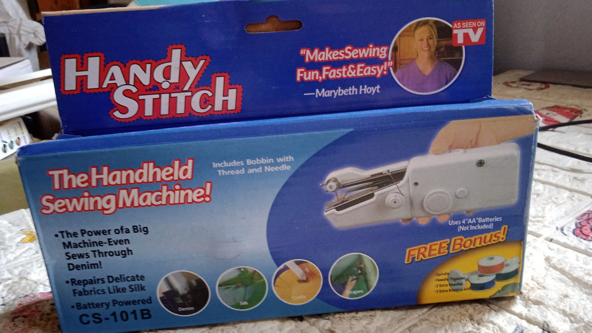 Two blue boxes for a "Handy Stitch" handheld sewing machine are stacked on a patterned surface.
