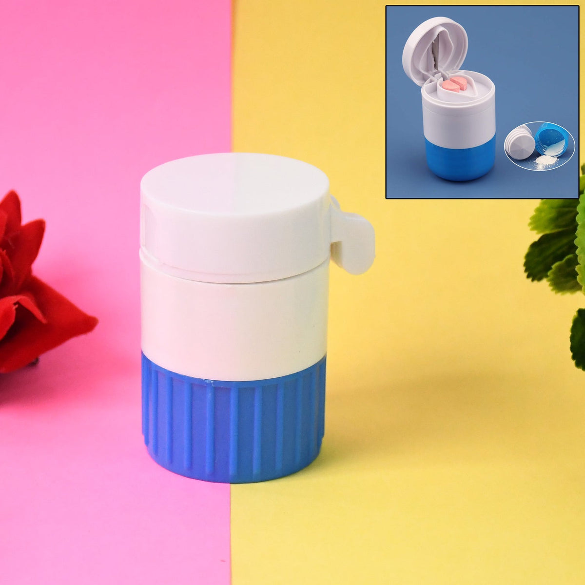 White and blue pill crusher and cutter on a pink and yellow background with green foliage.