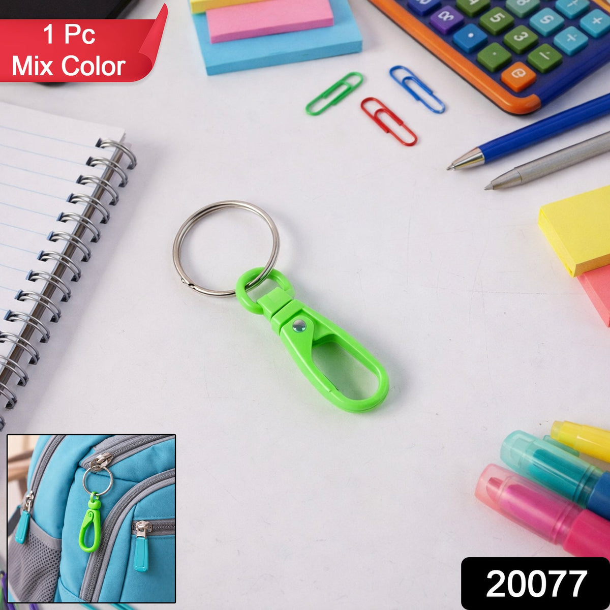 A green plastic carabiner keychain with a silver ring on a white desk with various school supplies.