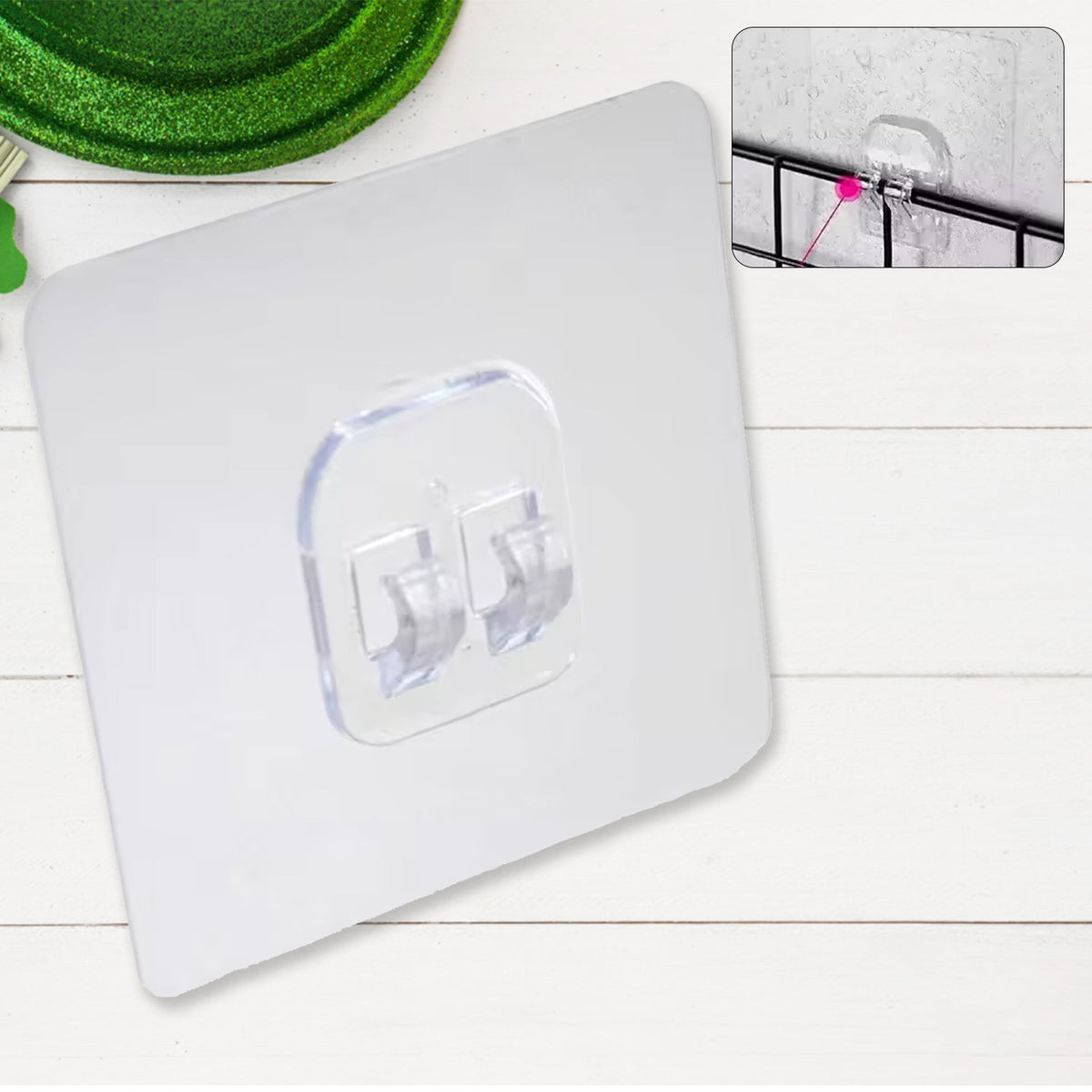 A clear self-adhesive wall hook is displayed on a white wooden background, with an inset showing it on a black grid.