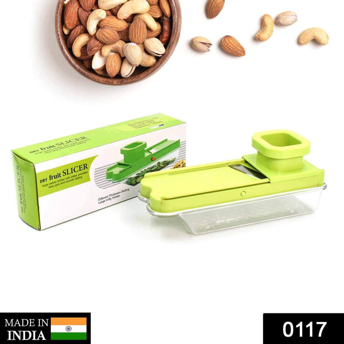 A green plastic dry fruit slicer with a clear container sits next to its green and white box, with nuts scattered around.