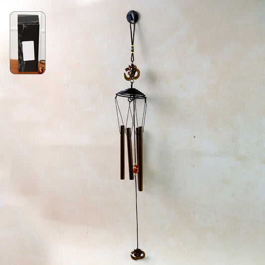 Metal wind chime with Om symbol hanging outdoors in a garden