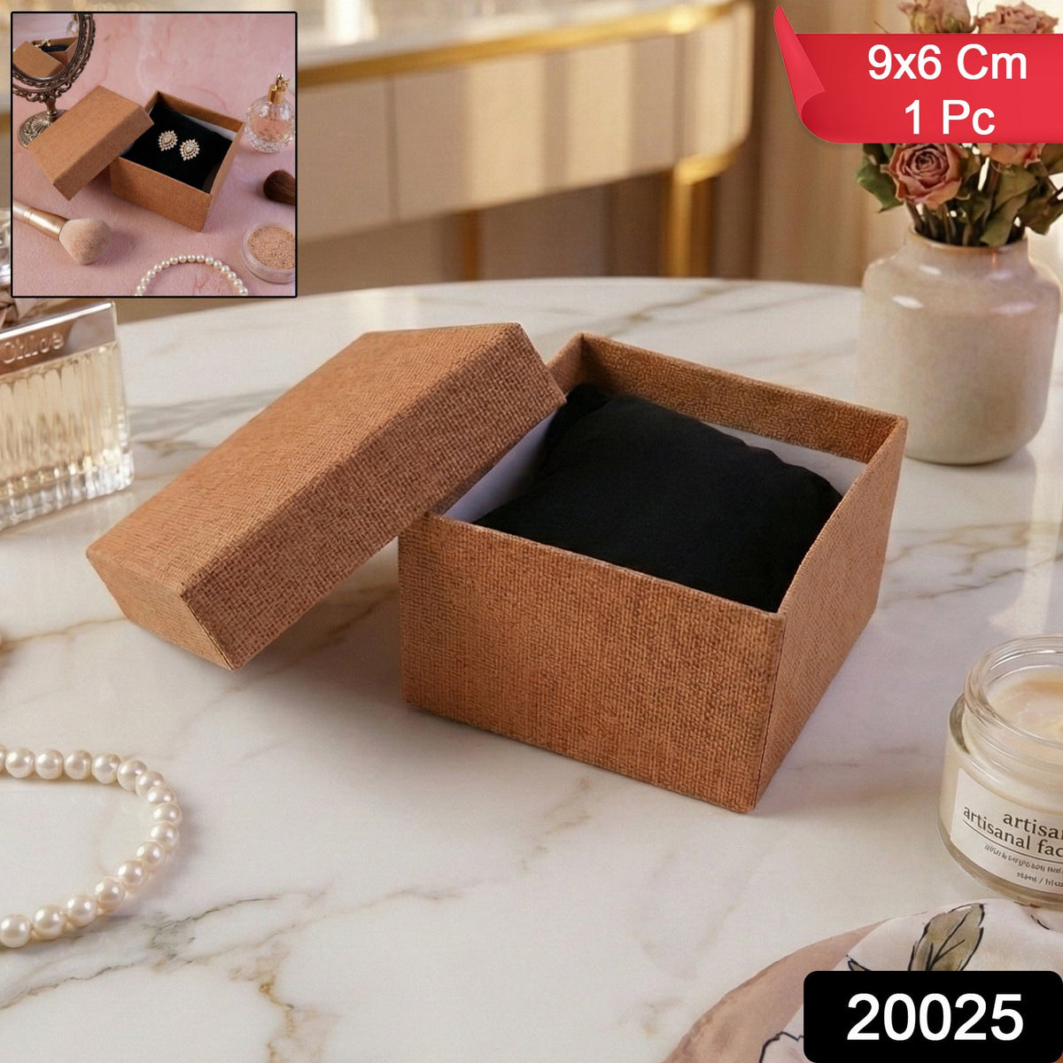 Brown textured gift box with the lid ajar, showing a dark cushion inside, next to pearl necklace and perfume.