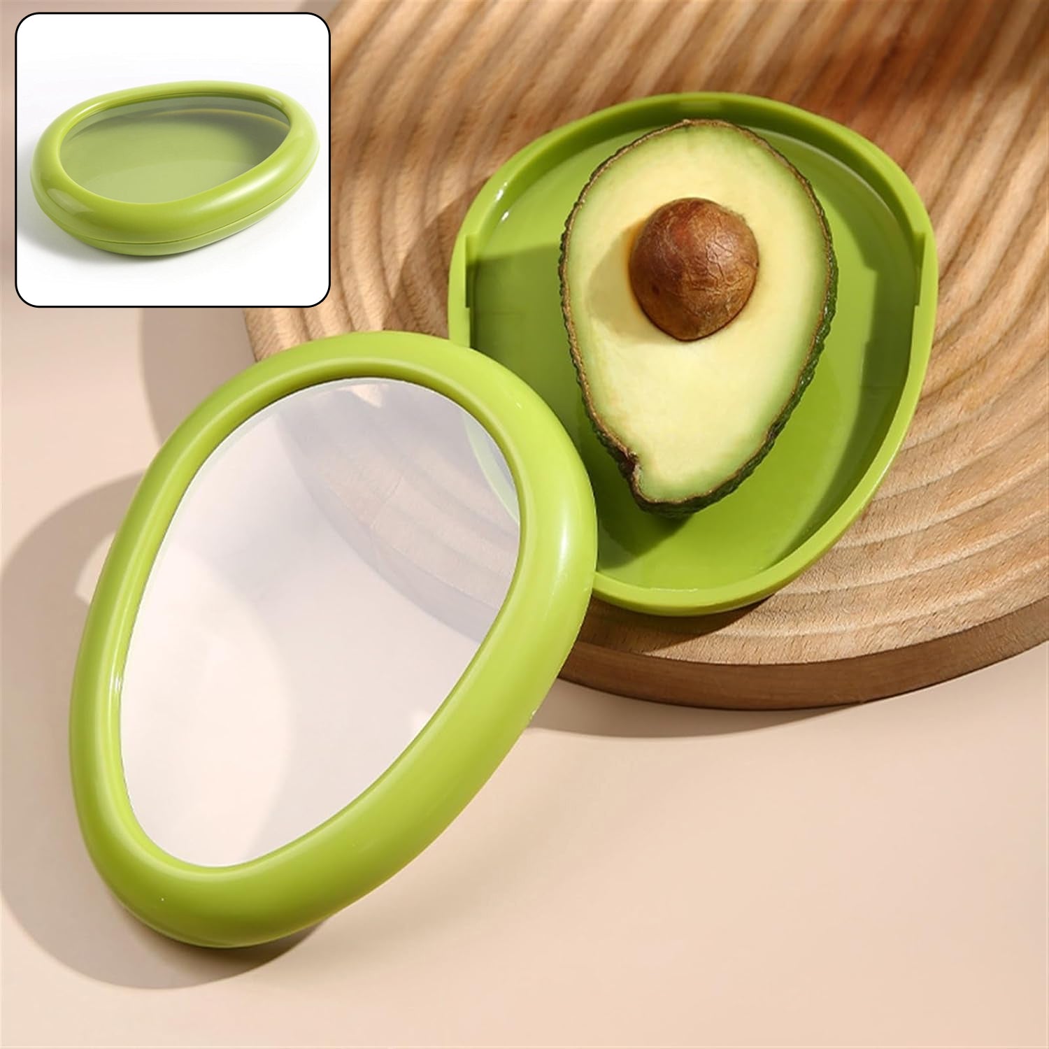 A green avocado-shaped container holds half an avocado on a wooden board, with a smaller inset image of the closed container.