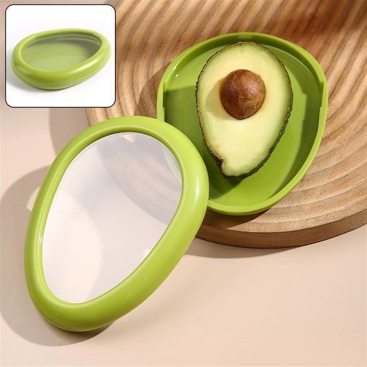 A green avocado-shaped container holds half an avocado on a wooden board, with a smaller inset image of the closed container.