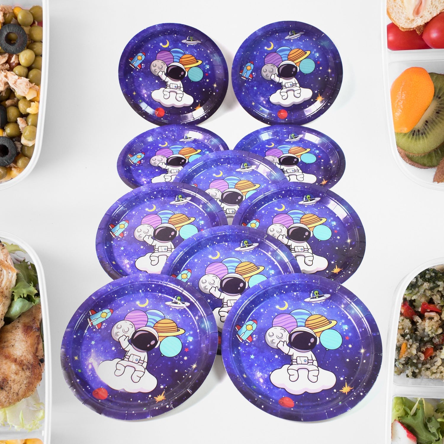 Ten purple paper plates with a cartoon astronaut and planets, arranged on a white surface with food containers.