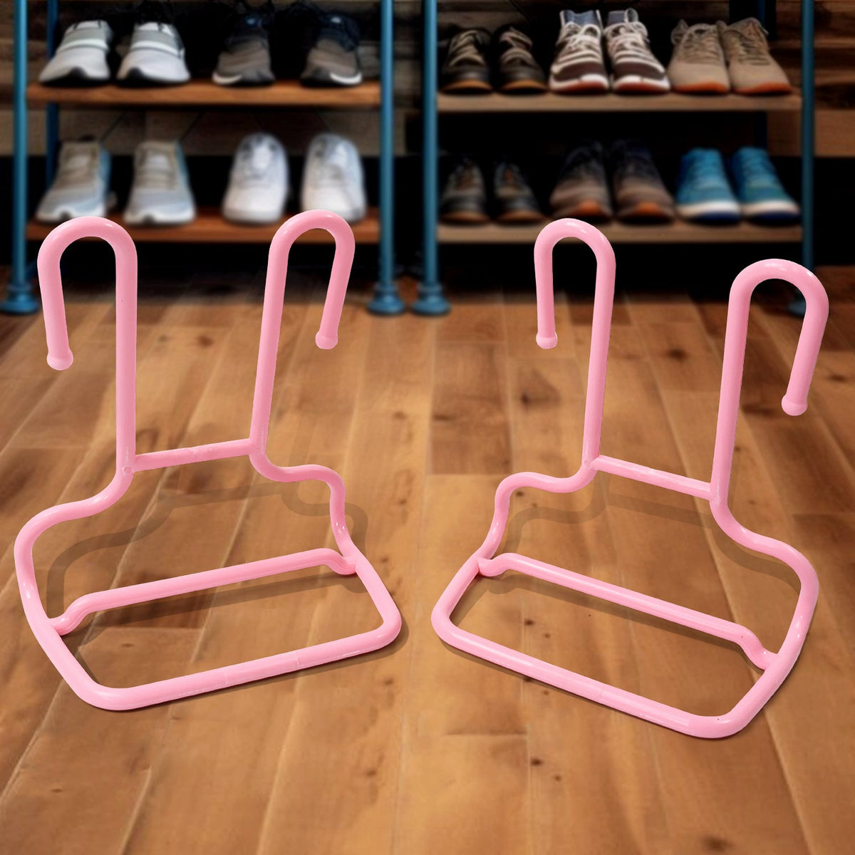 Two pink plastic shoe drying racks are on a wooden floor, with a blurred background of a shoe shelf.