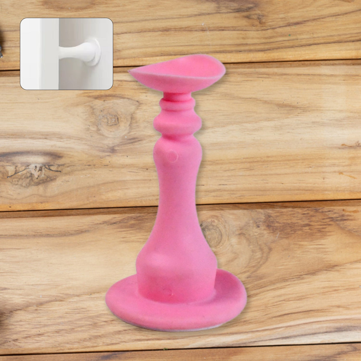 Pink silicone door stopper on a wooden surface, with a small inset of a white door stop attached to a wall.