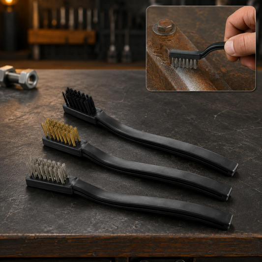 Three mini wire brushes with black handles and different bristle types on a dark, textured surface, with one brush cleaning