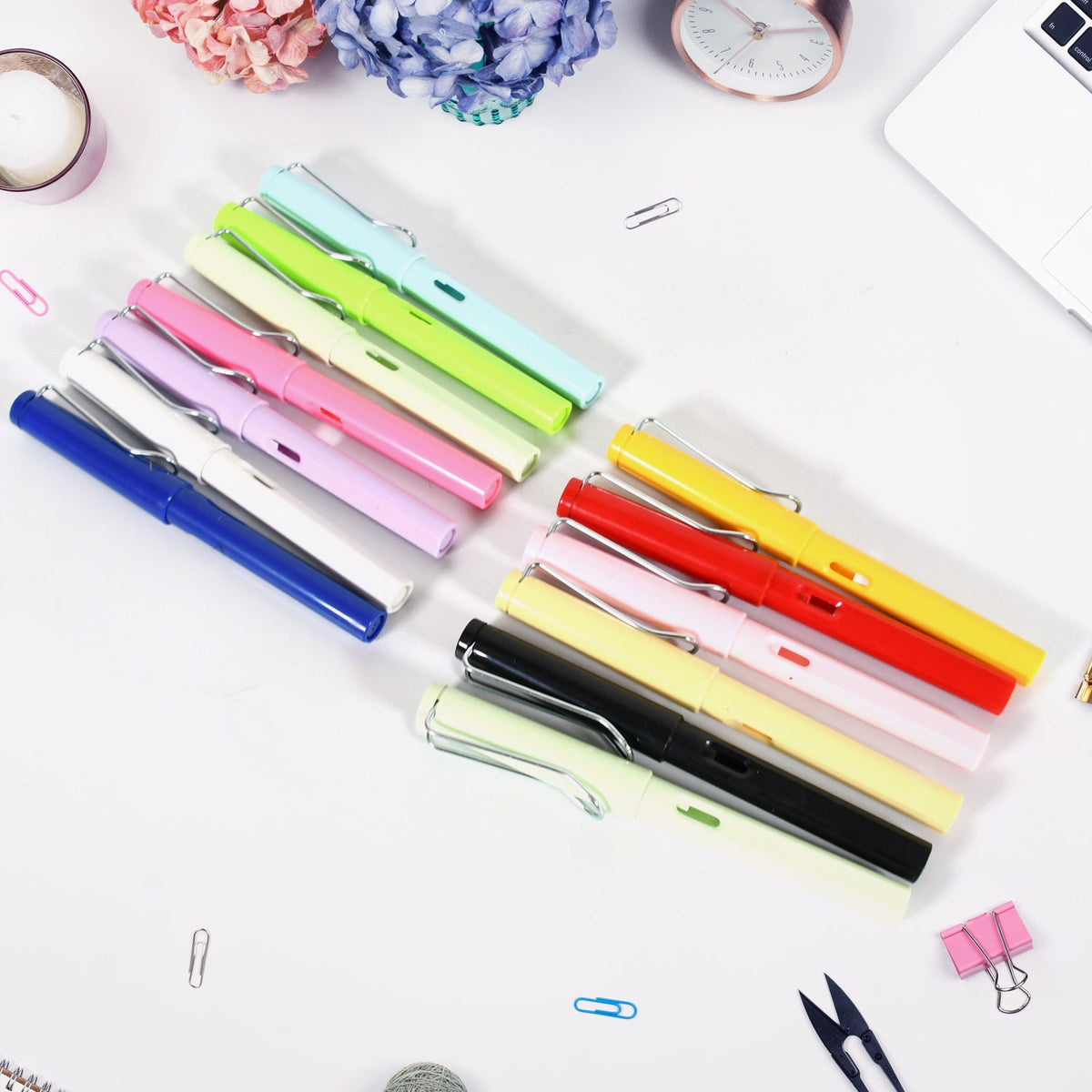 Various colorful inkless pencils are neatly arranged on a white desk with office supplies.