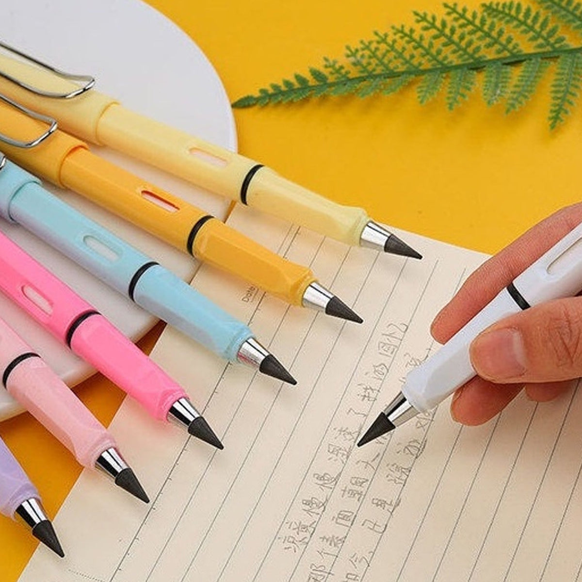 A hand writes with a white inkless pencil on a notebook, surrounded by other colorful pencils.
