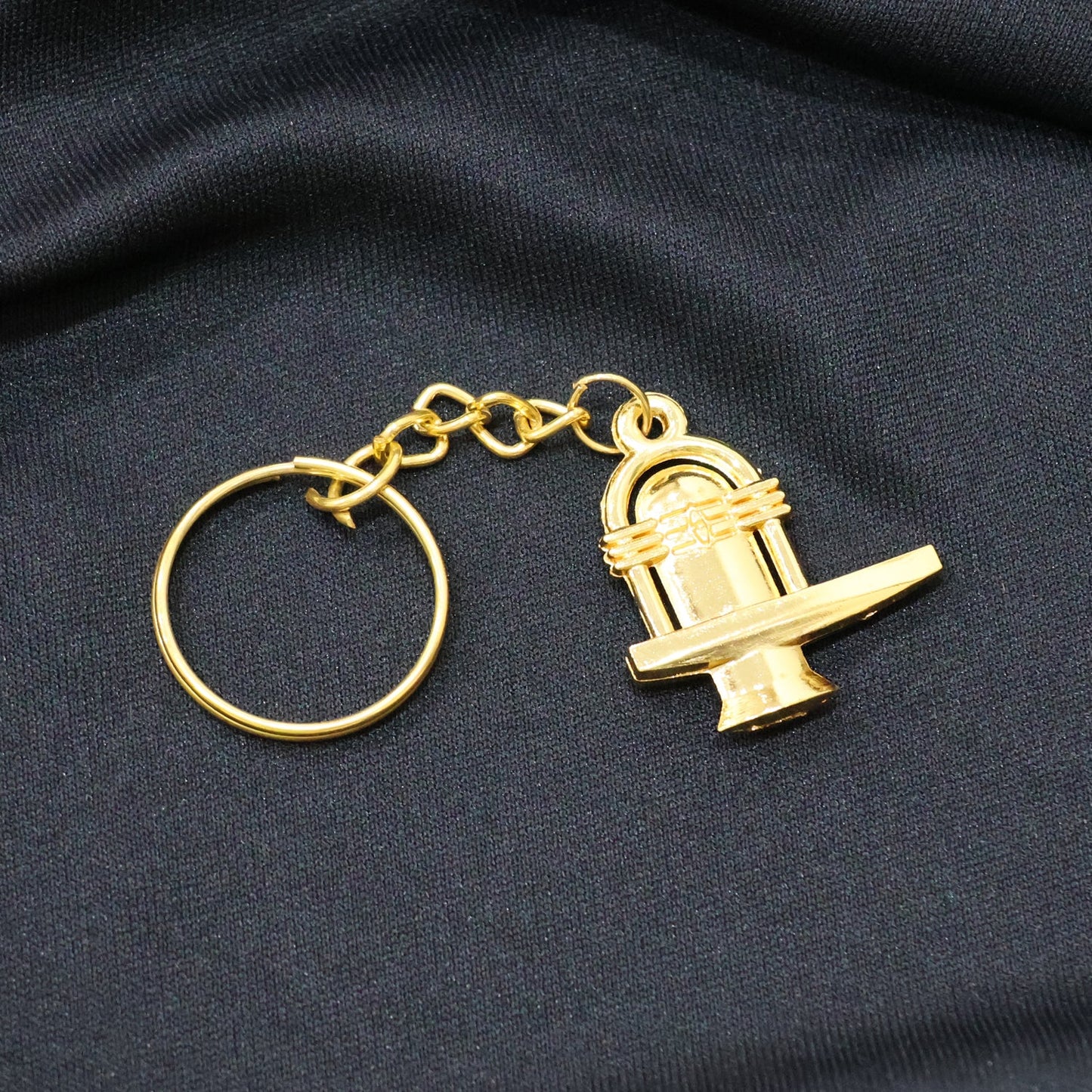 Golden Shivling metal keychain showcased alongside measuring scale revealing size
