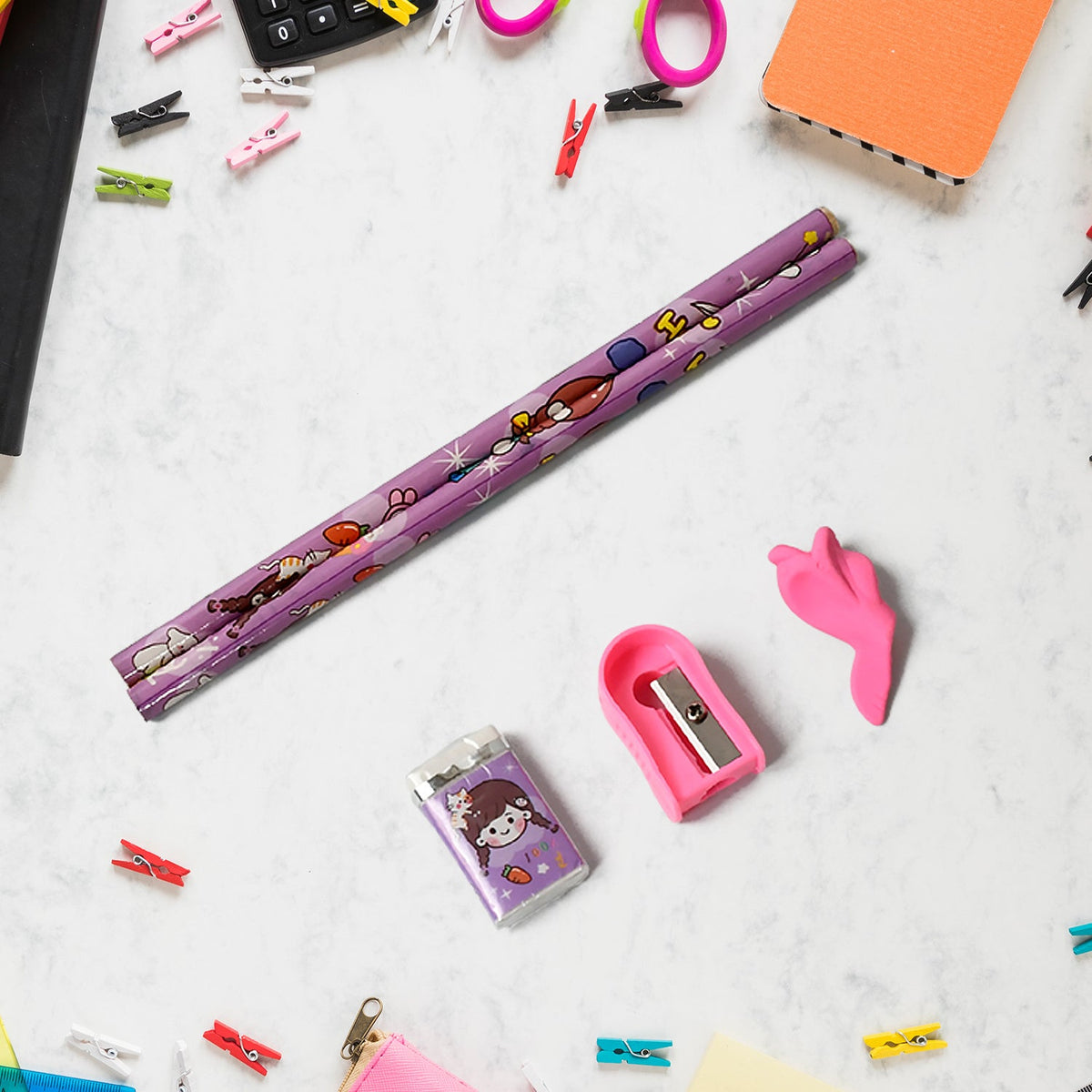 Two purple pencils with cartoon designs, a pink sharpener, and a purple eraser with a cartoon girl, on a white surface