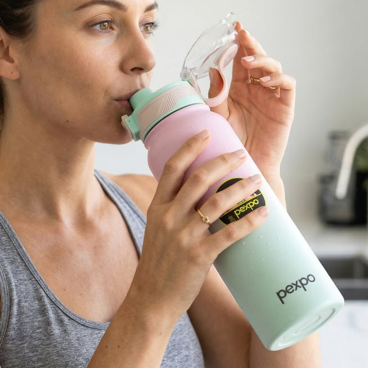 The pink and green gradient water bottle stands next to its packaging, which features a picture of a man.