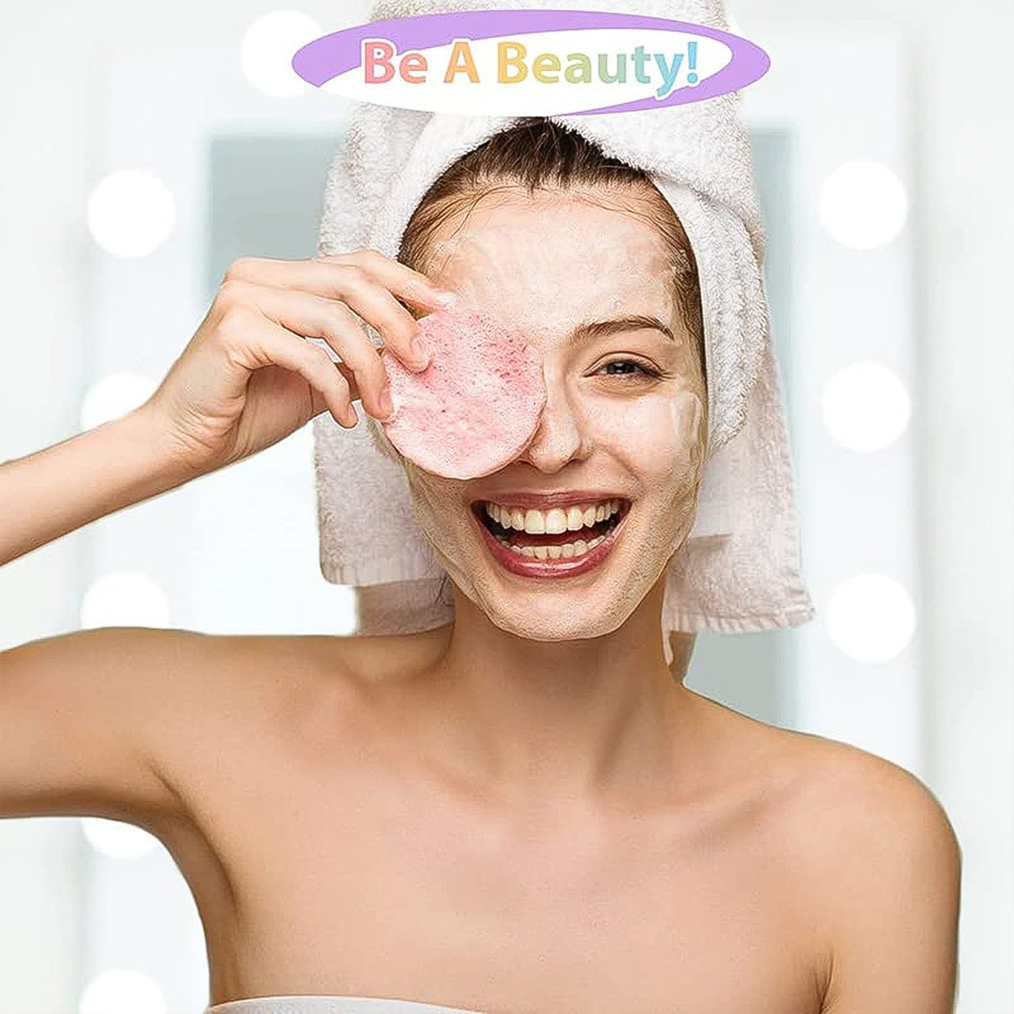 A smiling woman with a towel on her head holds two pink round makeup remover pads over one eye.