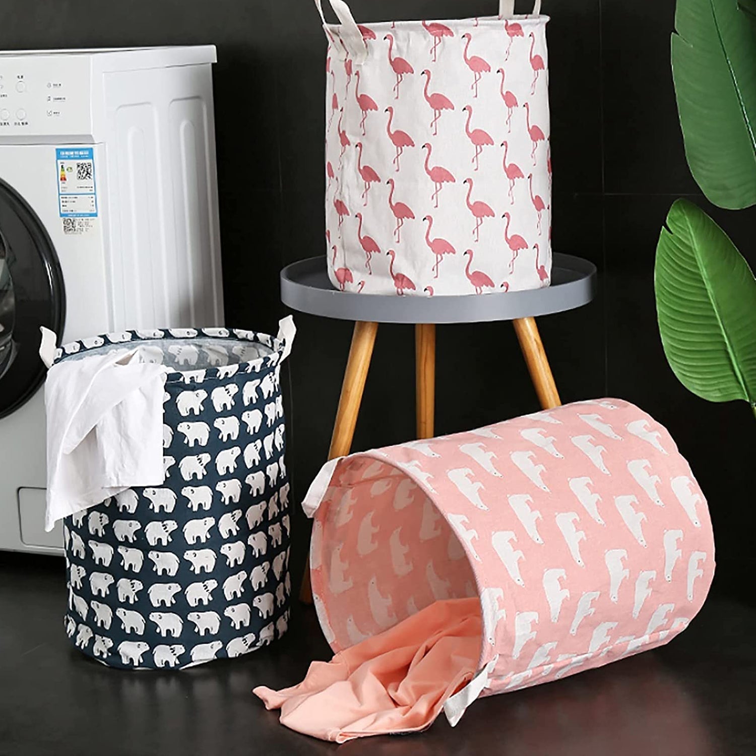 Three fabric laundry hampers: one dark blue with polar bears, one pink with polar bears, and one white with flamingos.