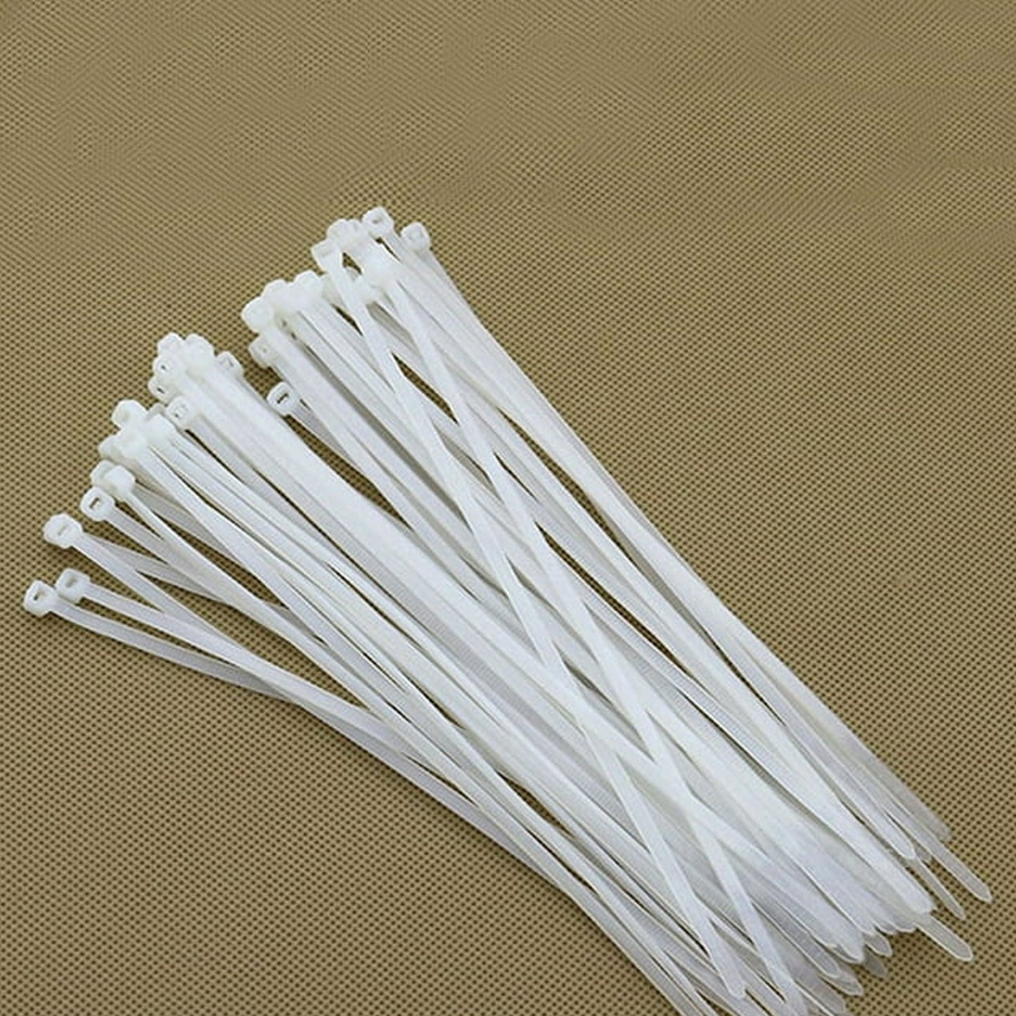 A large stack of white cable ties arranged neatly on a textured brown surface.
