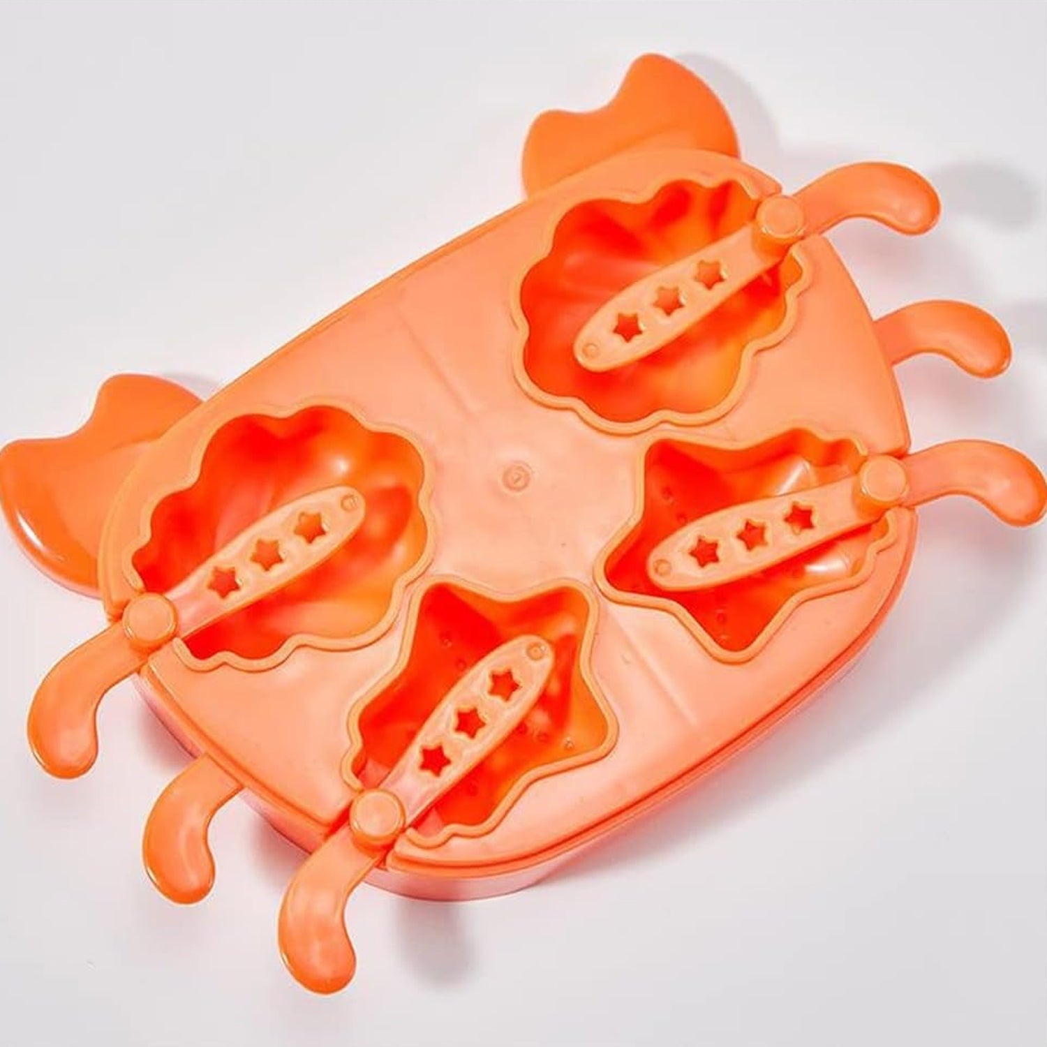 The orange crab ice mold with four popsicle sticks inserted into the molds, ready for freezing.