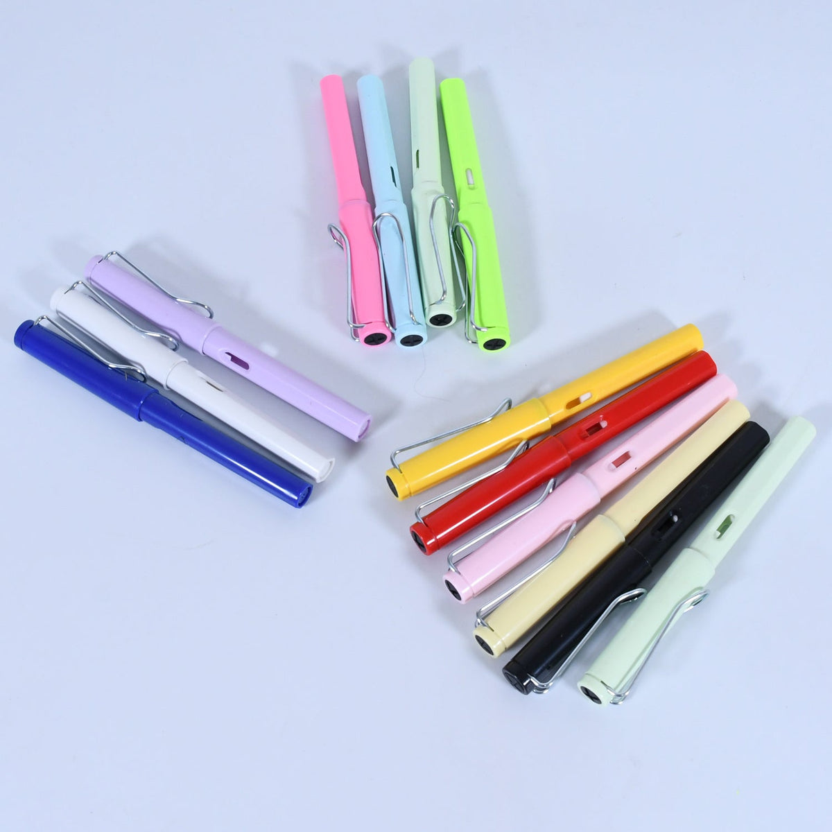 Groups of colorful inkless pencils are scattered on a plain white surface.