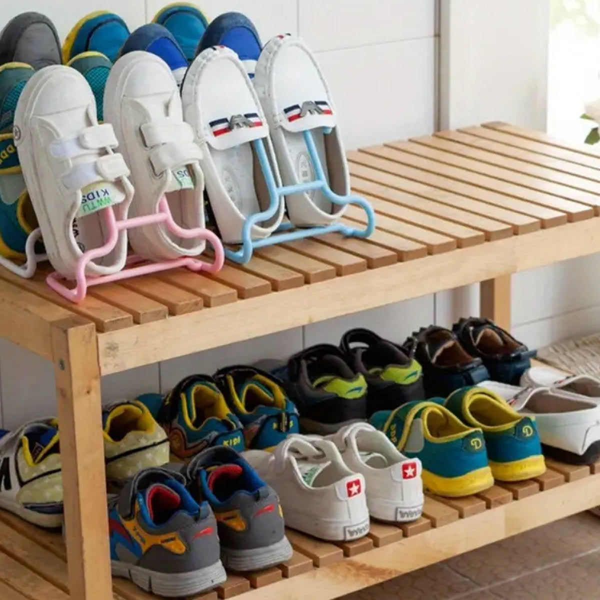 Several shoes are displayed on a wooden shoe rack, with some pairs hanging from pink and blue plastic hangers.