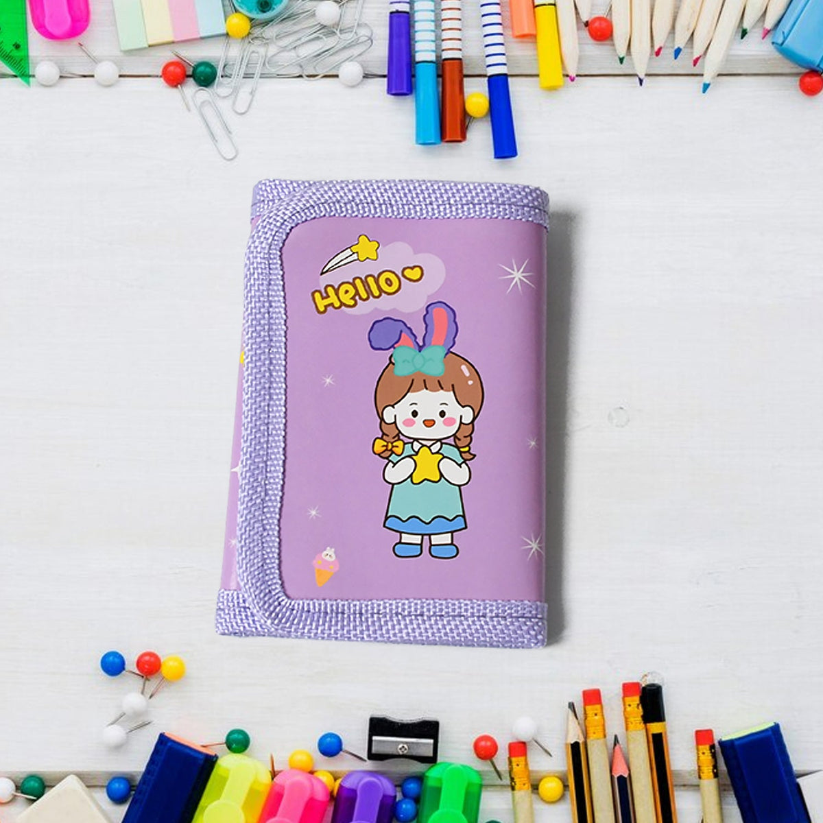 A closed purple wallet with a cartoon girl holding a star, on a white wooden surface surrounded by colorful pushpins and art