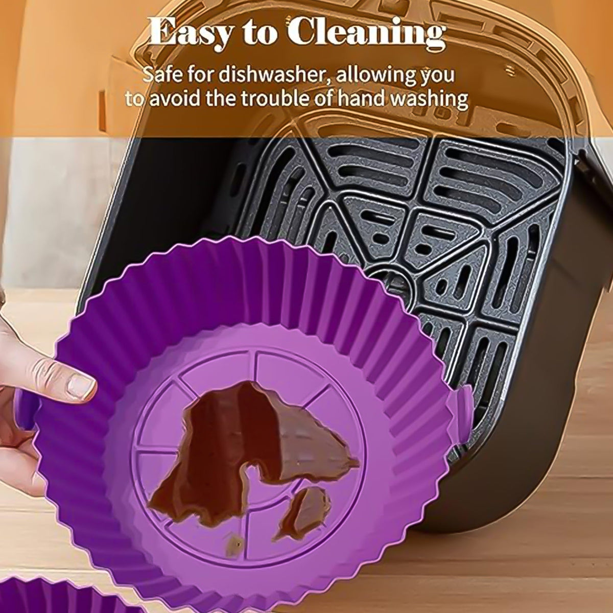A hand holds a dirty purple silicone air fryer pot with handles, next to an empty air fryer basket.