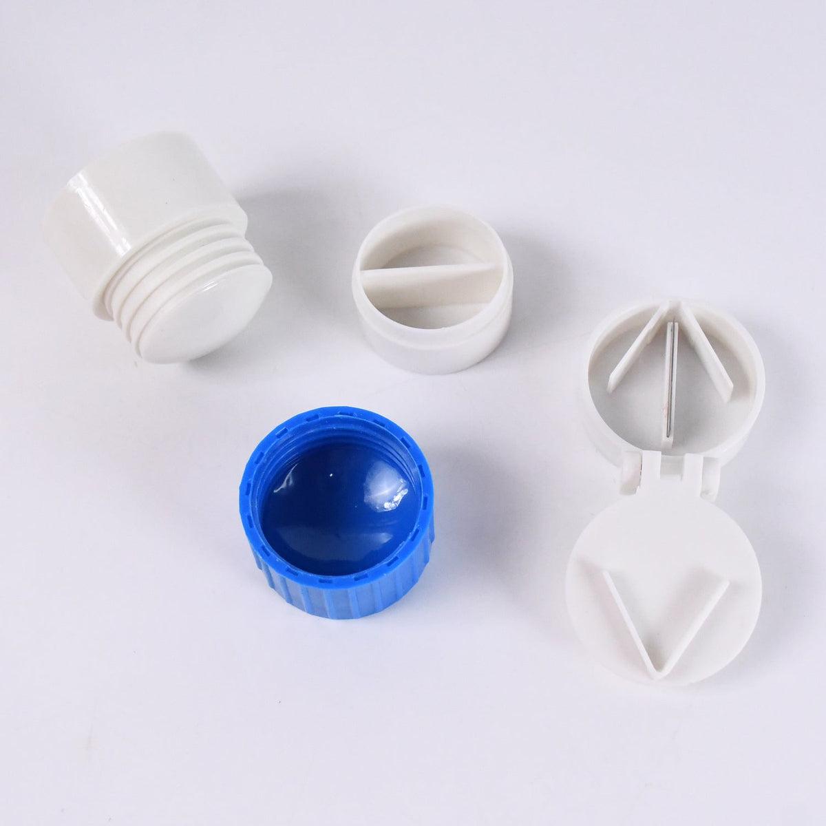 Disassembled parts of a pill crusher and cutter, including a blue base and white components.