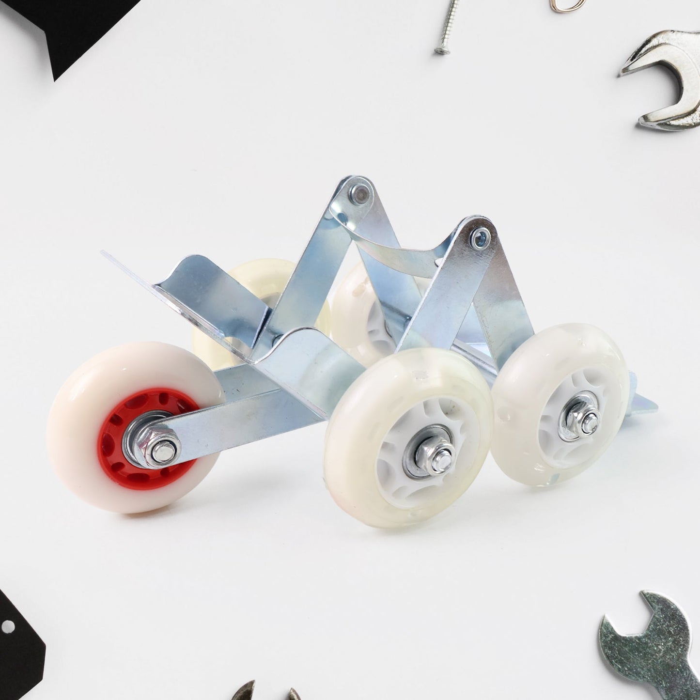 A silver metal roller stand with four white wheels and red accents is placed on a white surface with tools scattered around.