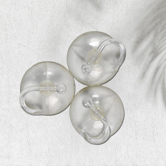Two transparent suction hooks with strong hold on a bathroom tile wall.