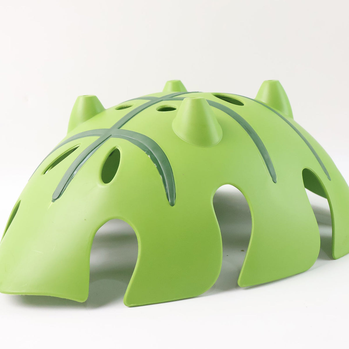 The underside of a green leaf-shaped plastic basket showing its three conical feet and dark green vein details.