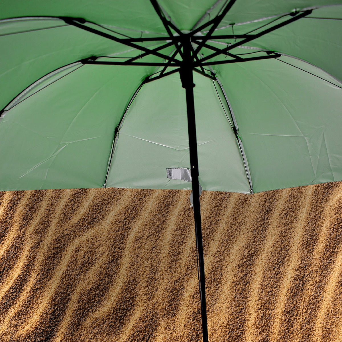 The underside of a green umbrella with black spokes is visible, positioned over a textured brown surface.