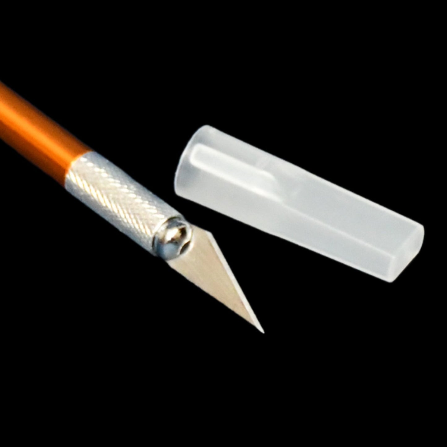 Close-up of the orange precision knife blade and silver grip with its clear protective cap.