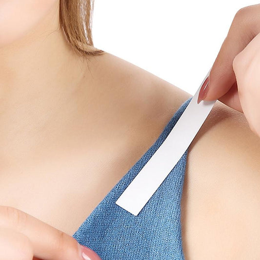 A person adheres a white strip of tape to the blue strap of a garment on their shoulder.