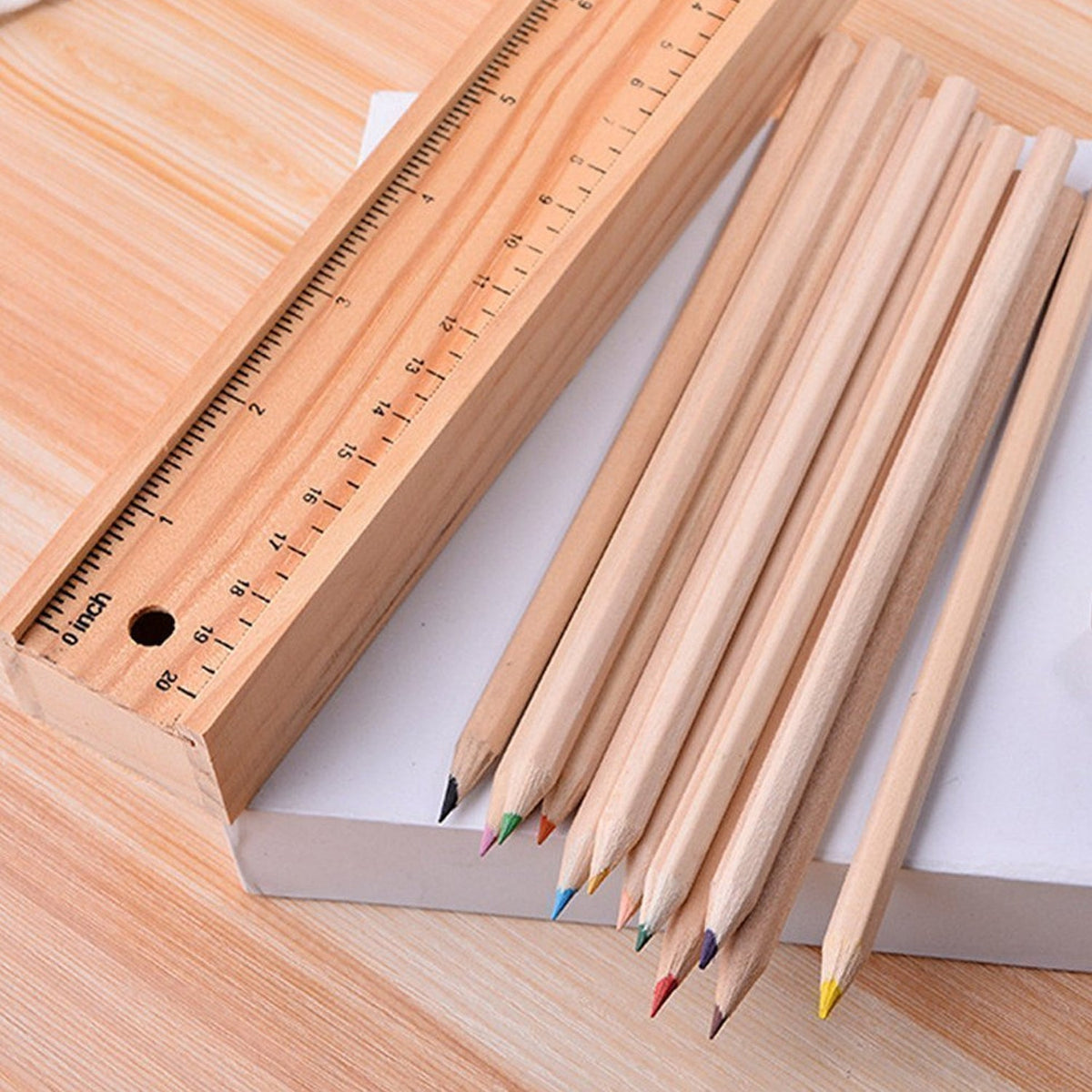 A close-up of the wooden ruler and 12 colored pencils with visible tips, resting on a white surface.
