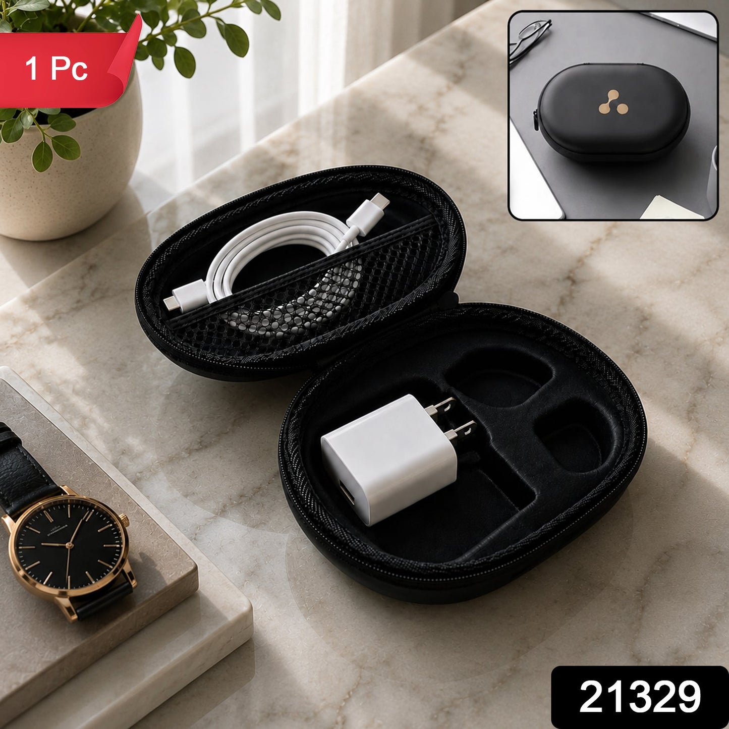 A closed black oval hard shell case with a gold three-dot logo rests on a white desk with a laptop and earbuds nearby.