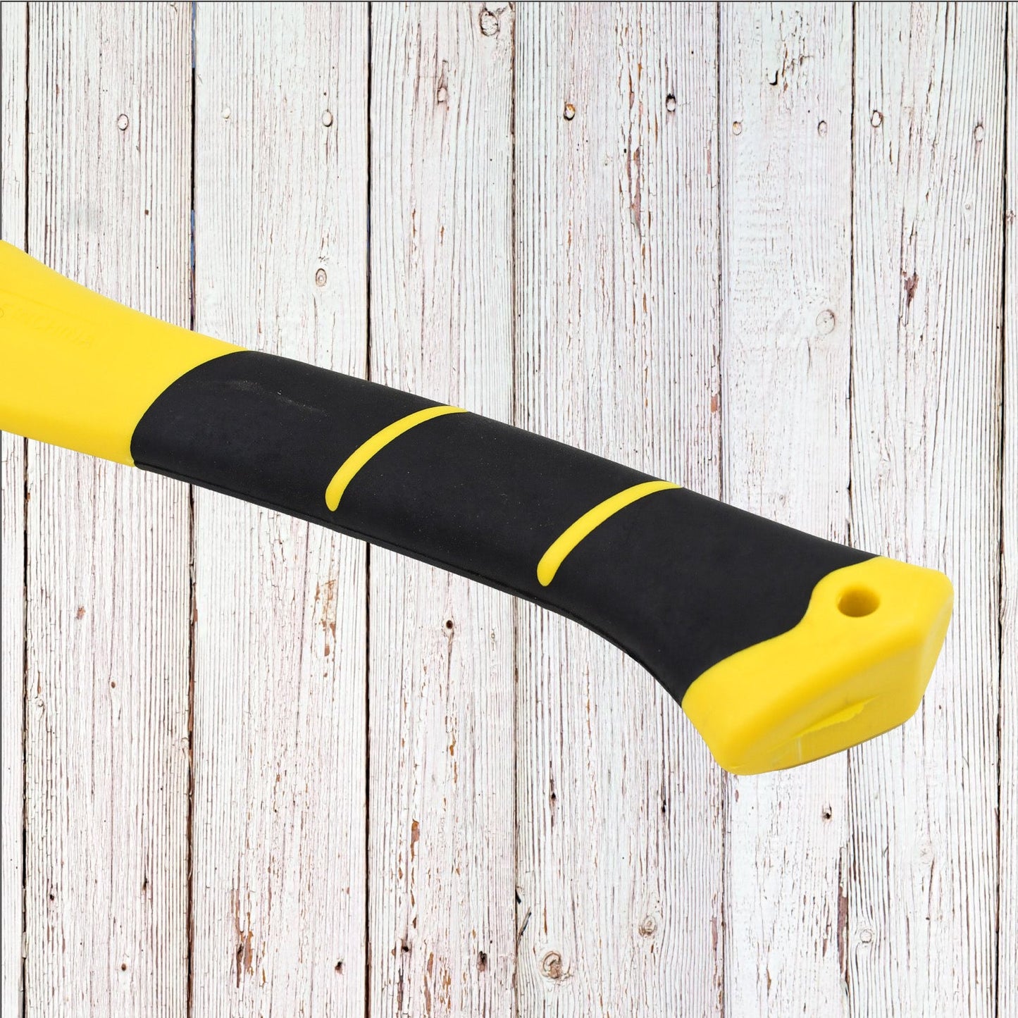 Close-up of the yellow and black textured handle of the hatchet axe against a white wooden background.