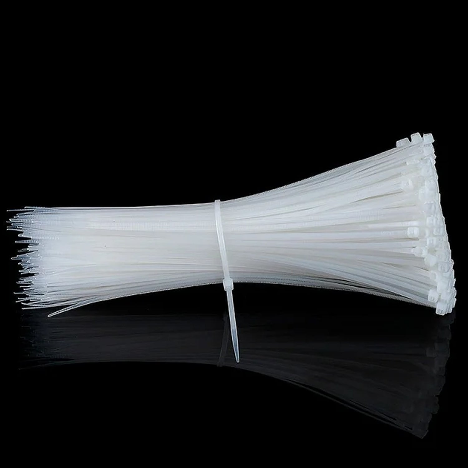A large bundle of white cable ties, secured together, lying on a reflective black surface.