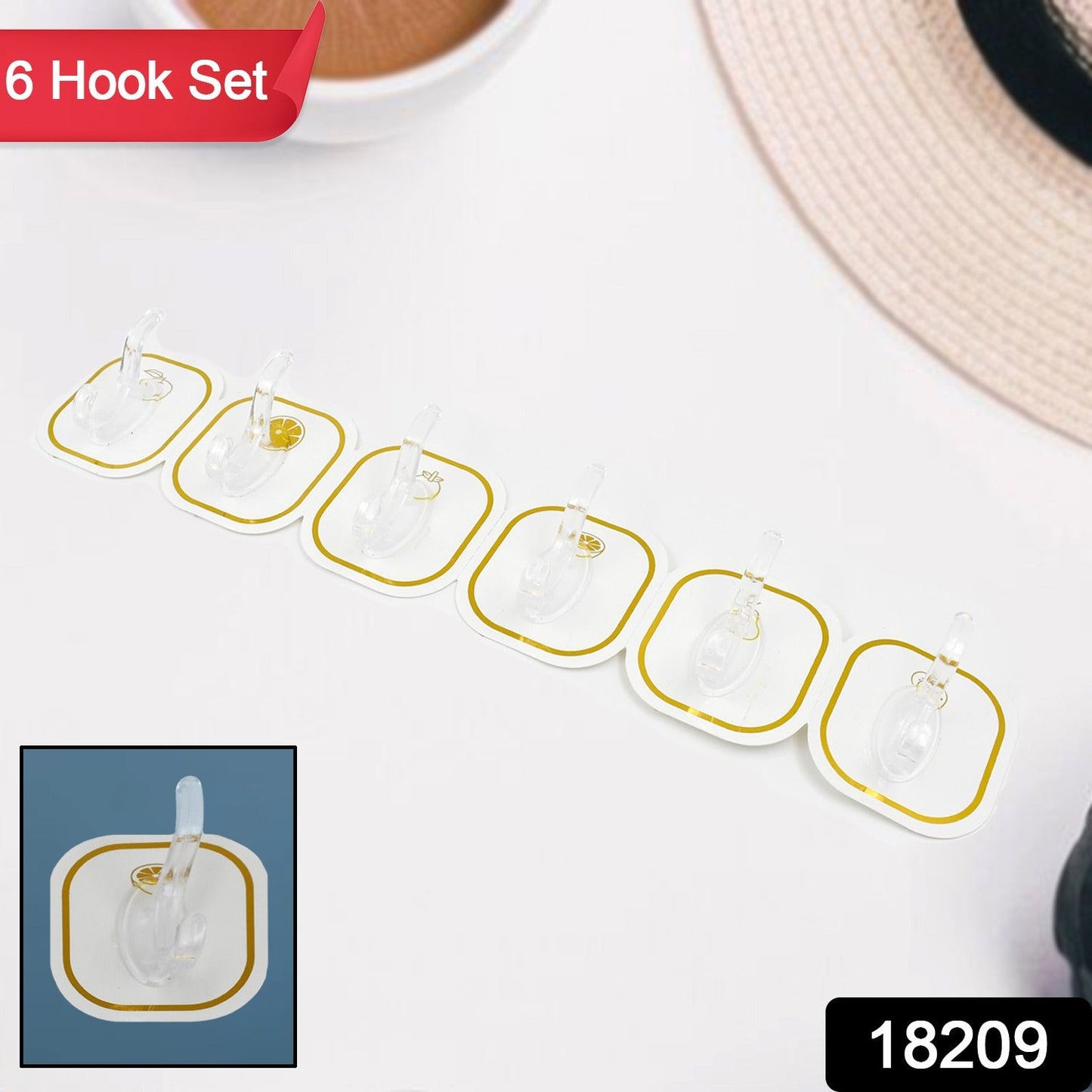 Six transparent adhesive hooks with gold borders arranged on a white surface, with a small inset showing one hook on a blue