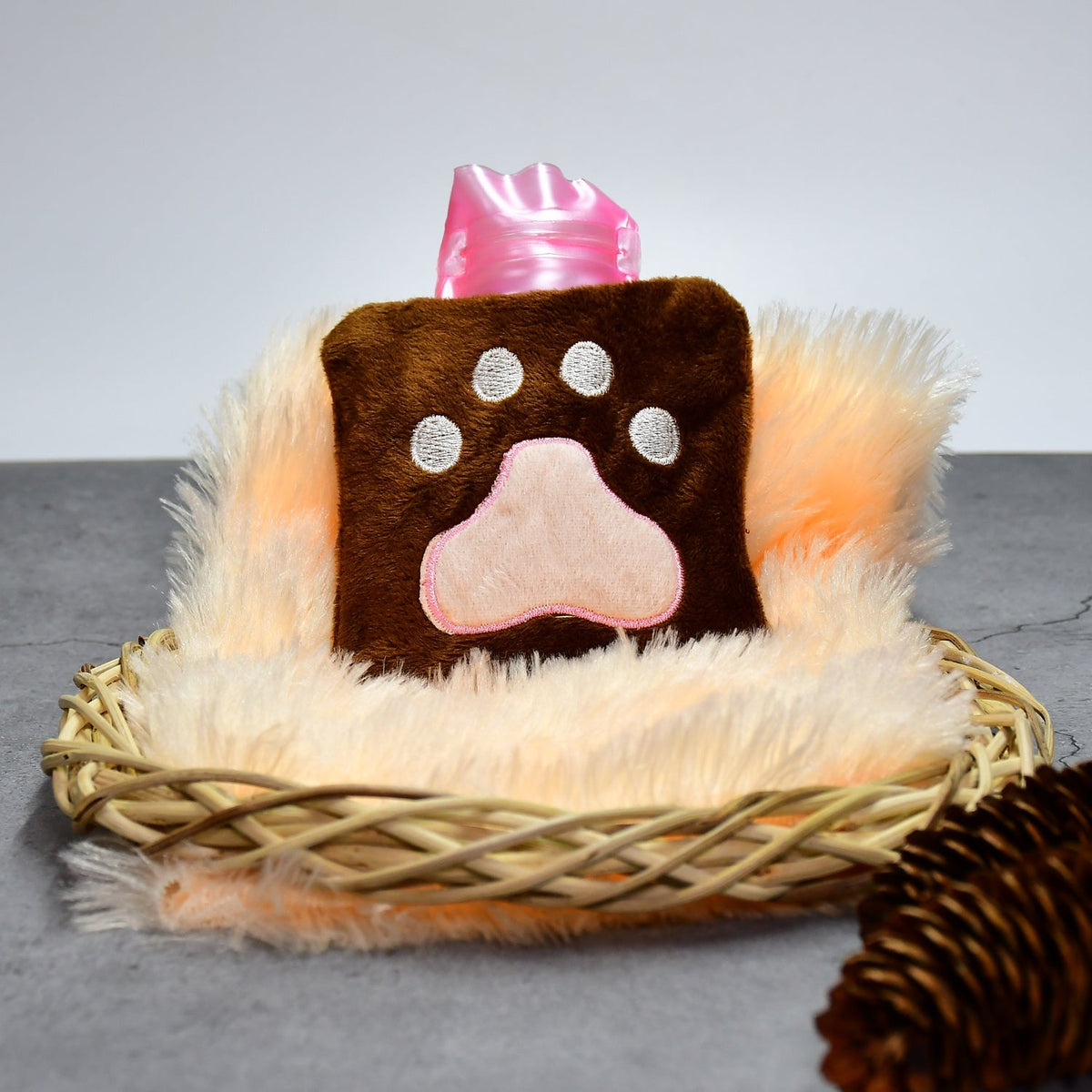 The brown paw print hot water bag is centered in a wicker basket with fluffy orange trim.